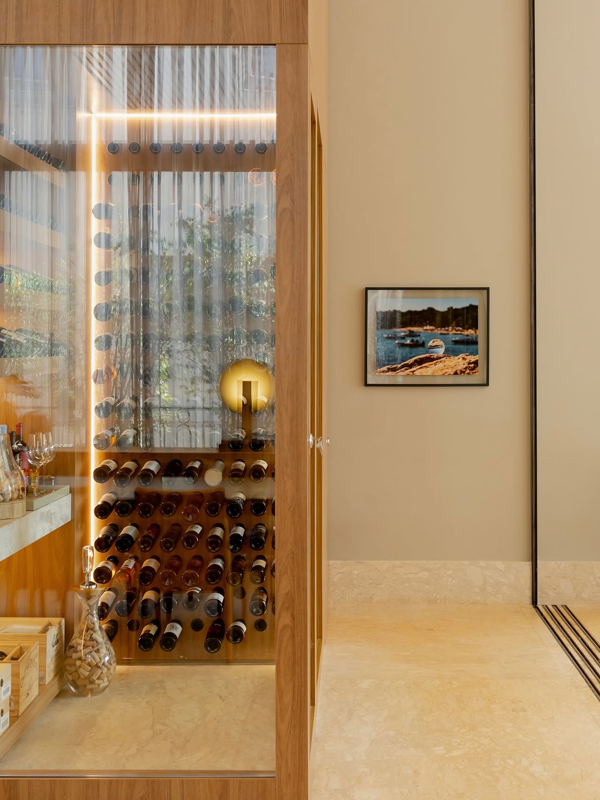 Detalhe da adega, com madeira, vidro e iluminação