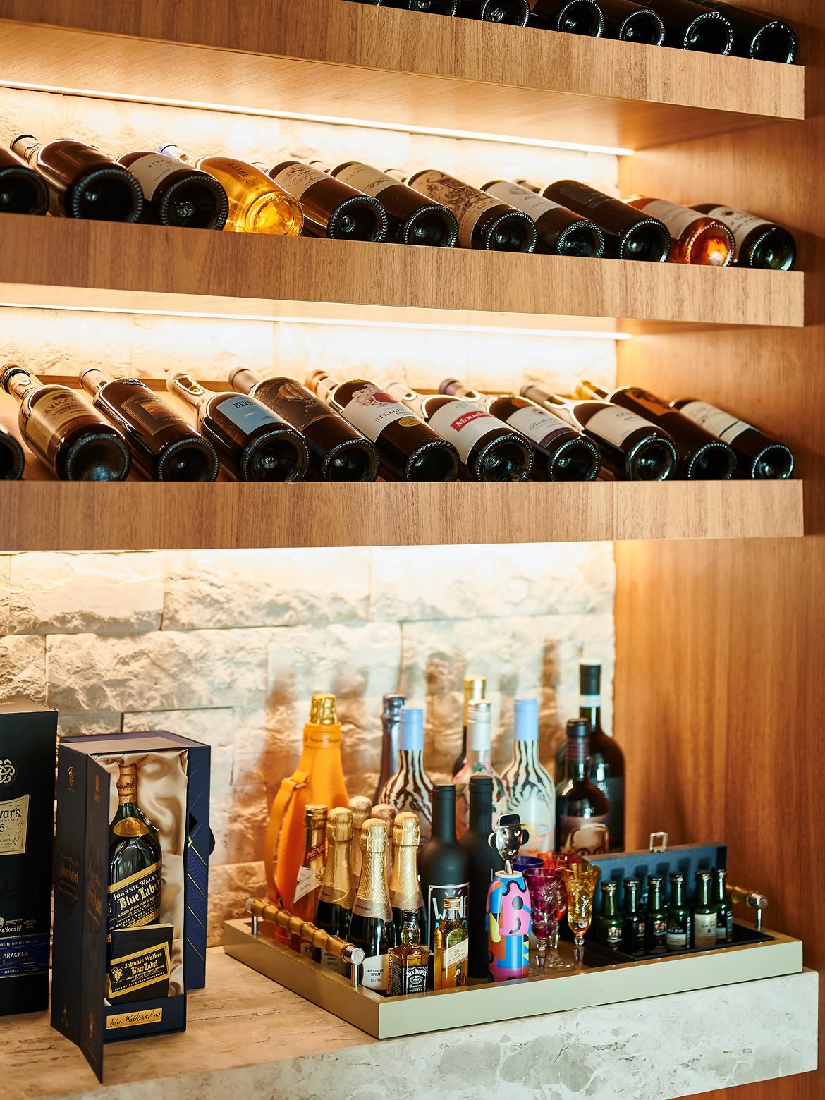 Detalhe da adega, com madeira, vidro e iluminação