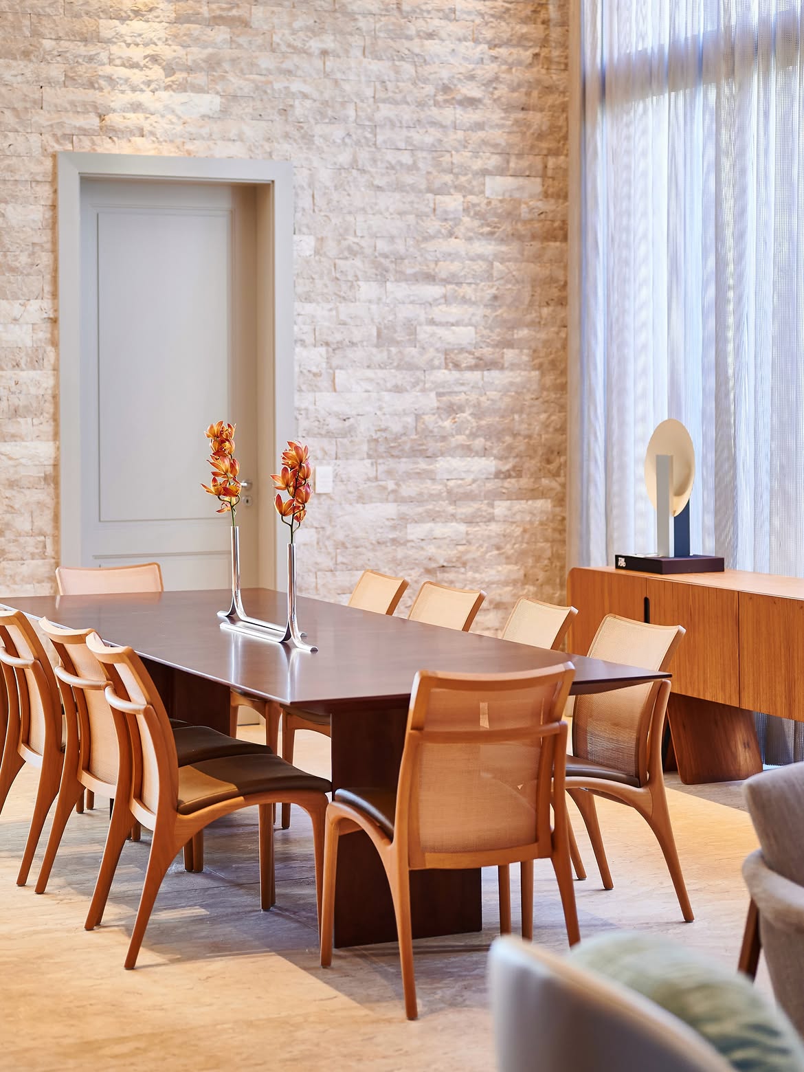 Sala de jantar com parede de pedra, mesa e cadeiras de madeira
